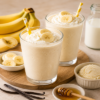 Romige banaan vanille milkshake met slagroom, banaanschijfjes, honing en vanille-ijs