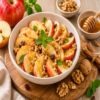 Gezonde appelsalade met verse rode appelpartjes, walnoten, rozijnen, honing en kaneel in een kom. Voedzaam ontbijt, gezonde snack of dessert met fruit en noten.