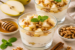 Glazen met romig perendessert, gegarneerd met stukjes peer, walnoten en munt, geserveerd met verse peren, honing en kaneelstokjes.